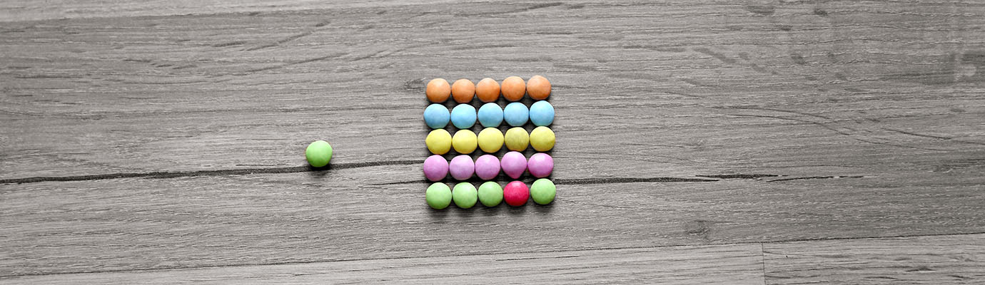 Smarties liegen wie ein Rechenschieber auf dem Boden, eines passt nicht zu den anderen Farben