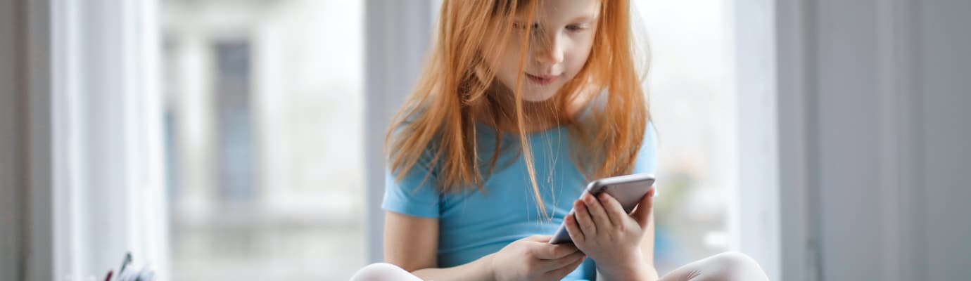 Little girl holds a smartphone in her hands.