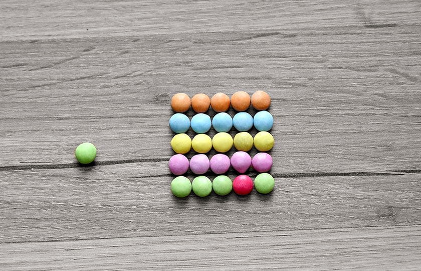 Smarties liegen wie ein Rechenschieber auf dem Boden, eines passt nicht zu den anderen Farben