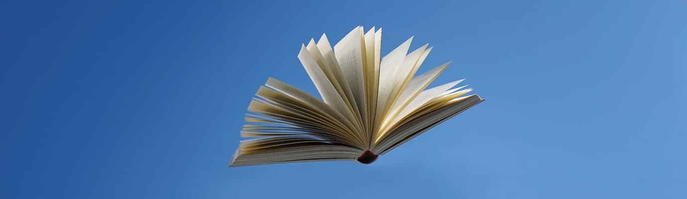 flying book with open pages in front of a blue sky