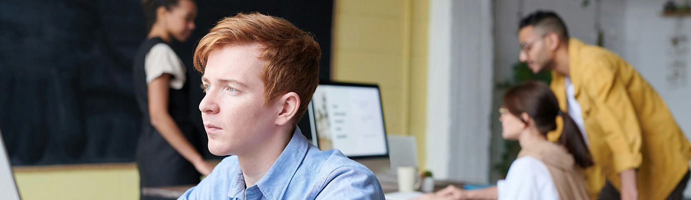 Junge Erwachsene im Klassenraum vor Laptops