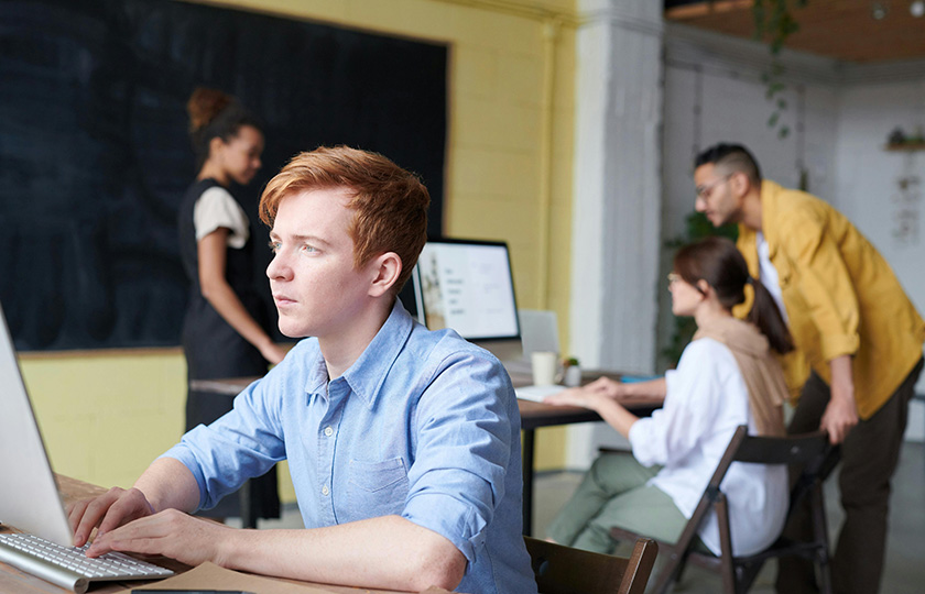 Junge Erwachsene im Klassenraum vor Laptops