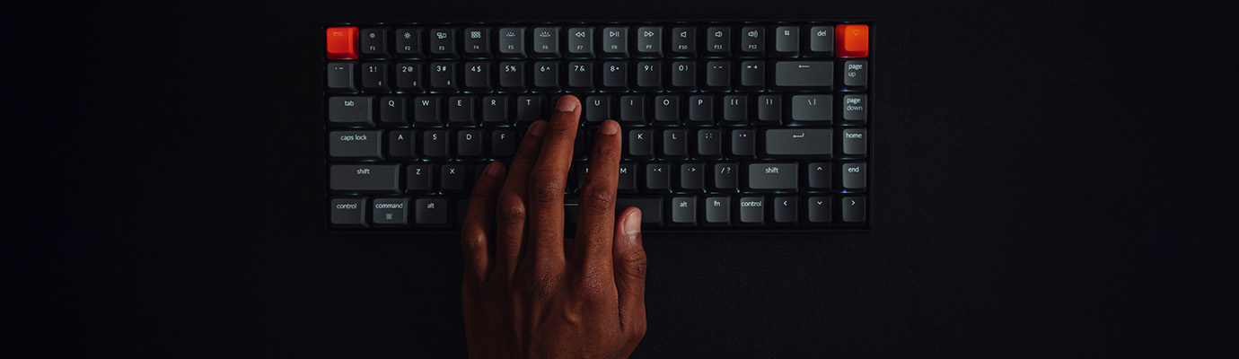 Personenhand auf Tastatur vor schwarzem Grund