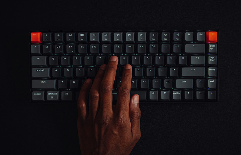 Personenhand auf Tastatur vor schwarzem Grund