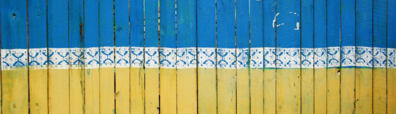 Eine Holzwand, gestrichen in den Farben blau und gelb.