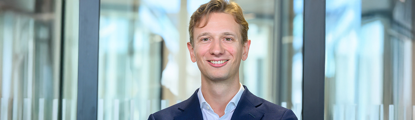Portrait Christian Ollig vor lichtdurchfluteten Glasscheiben